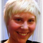 woman with short, platinum blonde hair smiling at the camera after makeover