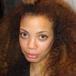 A close-up of a woman with voluminous, curly hair before haircut