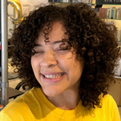 Woman in yellow shirt with short black curly hair