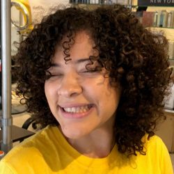 Woman in yellow shirt with short black curly hair