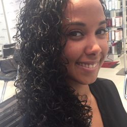 A woman with curly black hair smiling at a salon