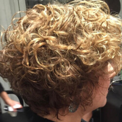 A person with short, curly light brown hair is shown from the side