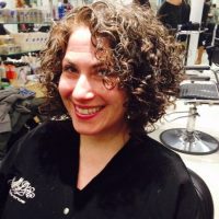 Woman with dark brown short curly hair
